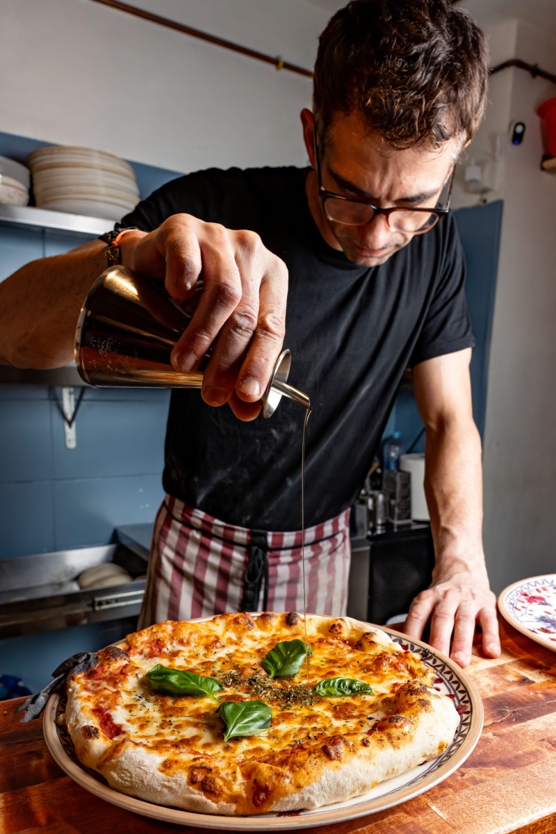 Pizzero añadiendo aceite