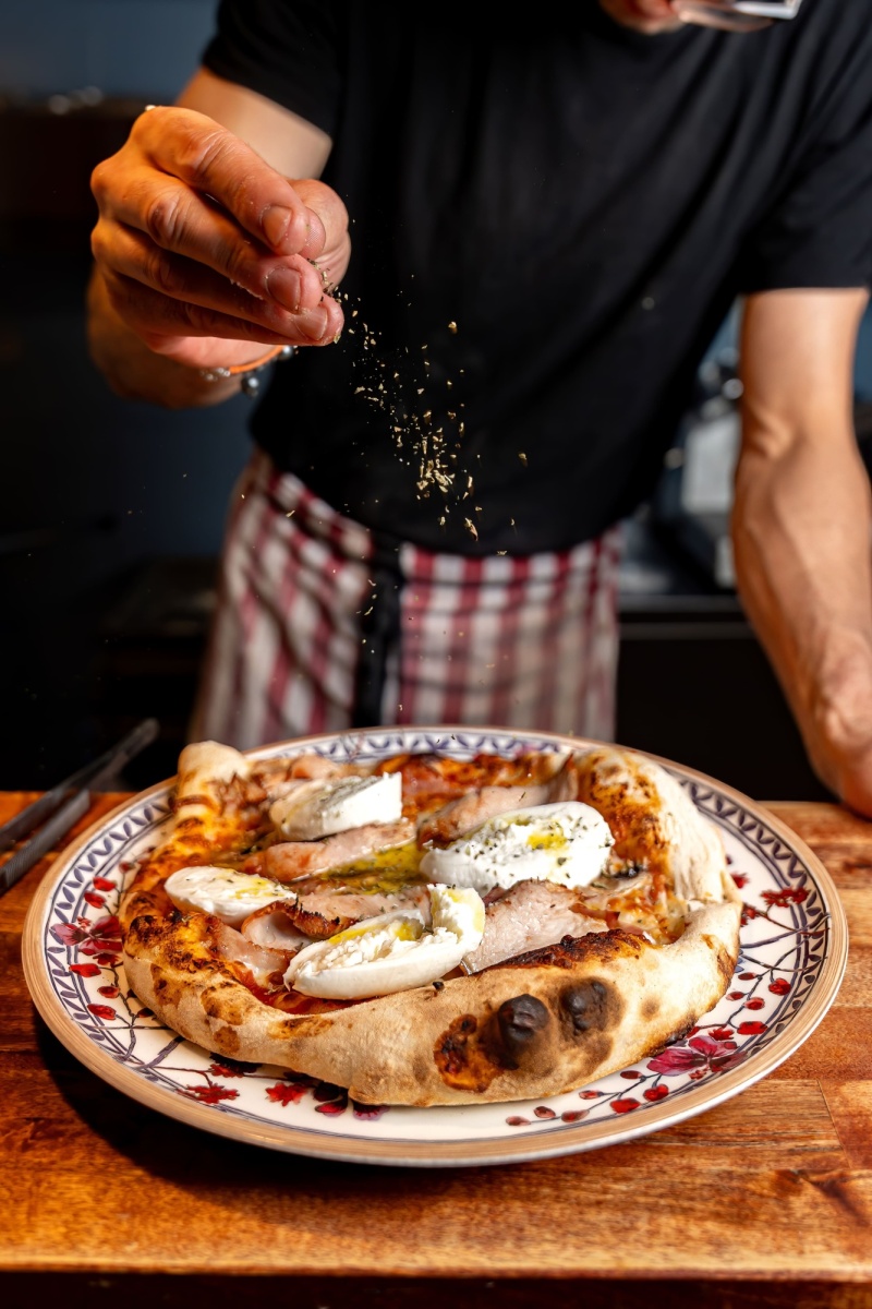 Pizzero poniendo orégano